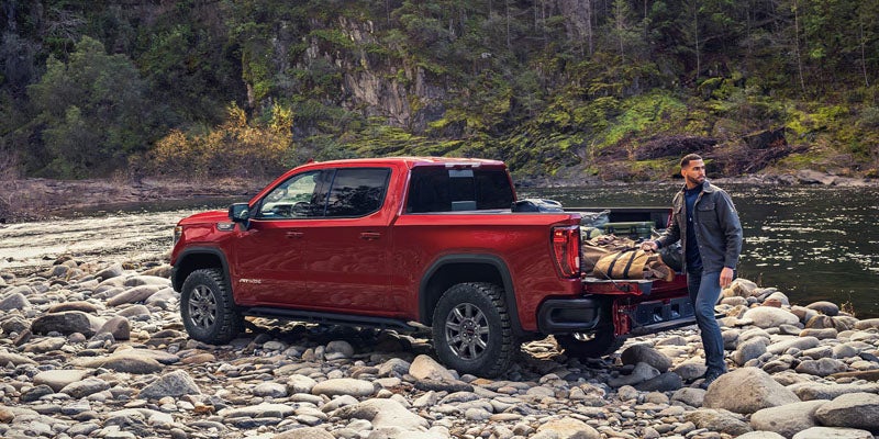 Red GMC Sierra 1500 parked on a rocky riverbank